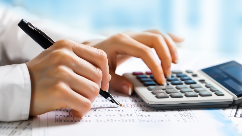 Osoba računa na kalkulatoru i popunjava papire